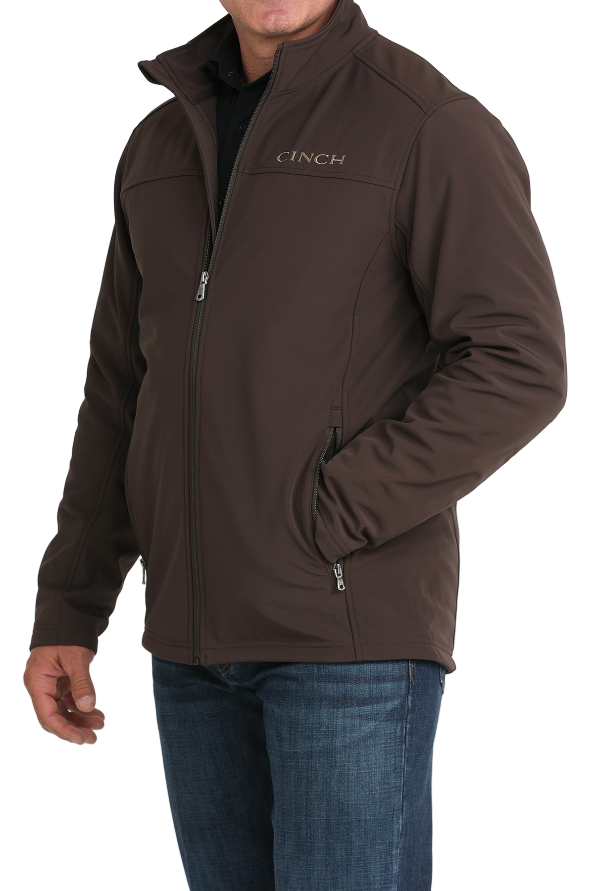 Man wearing a brown CINCH jacket with a full front zipper, paired with a black shirt and blue jeans