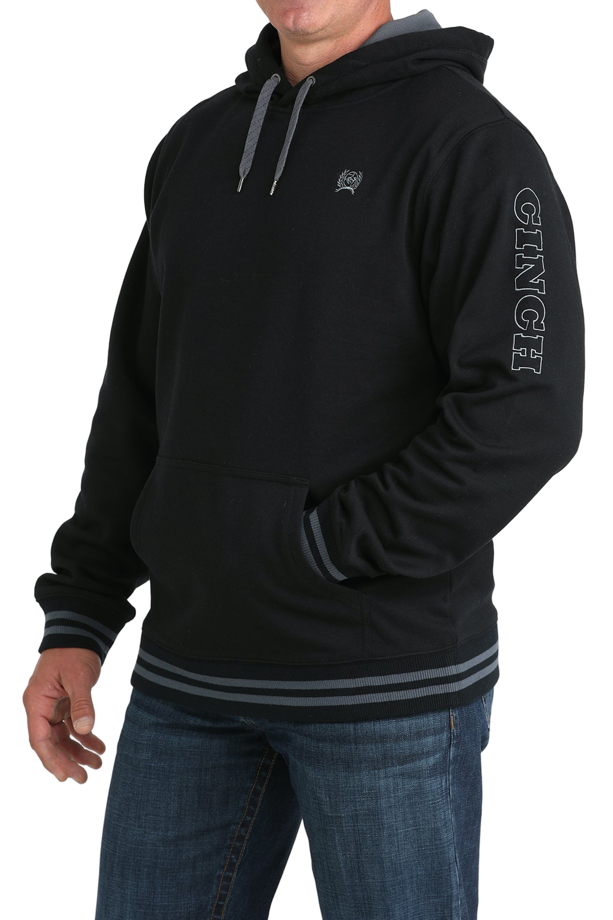 Man wearing a black hoodie with a small 'Cinch' logo on the chest, and 'Cinch' logo down the arm, paired with jeans on a transparent background