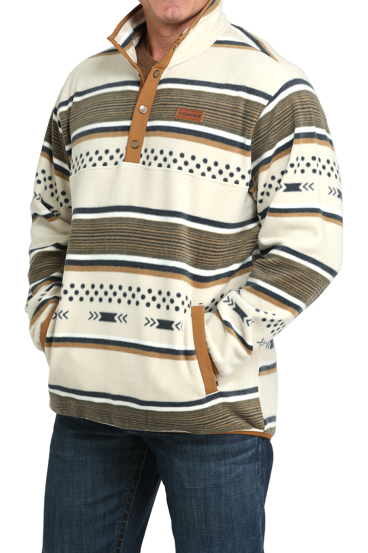 Man wearing a cream and tan striped pullover with a buttoned placket and side pockets, paired with blue jeans