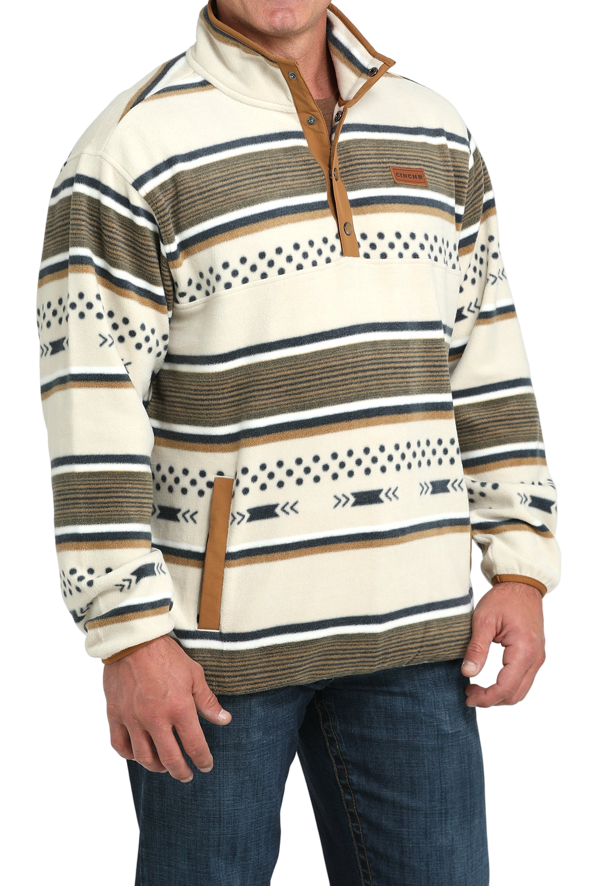 Man wearing a cream and tan striped pullover with a buttoned placket and side pockets, paired with blue jeans