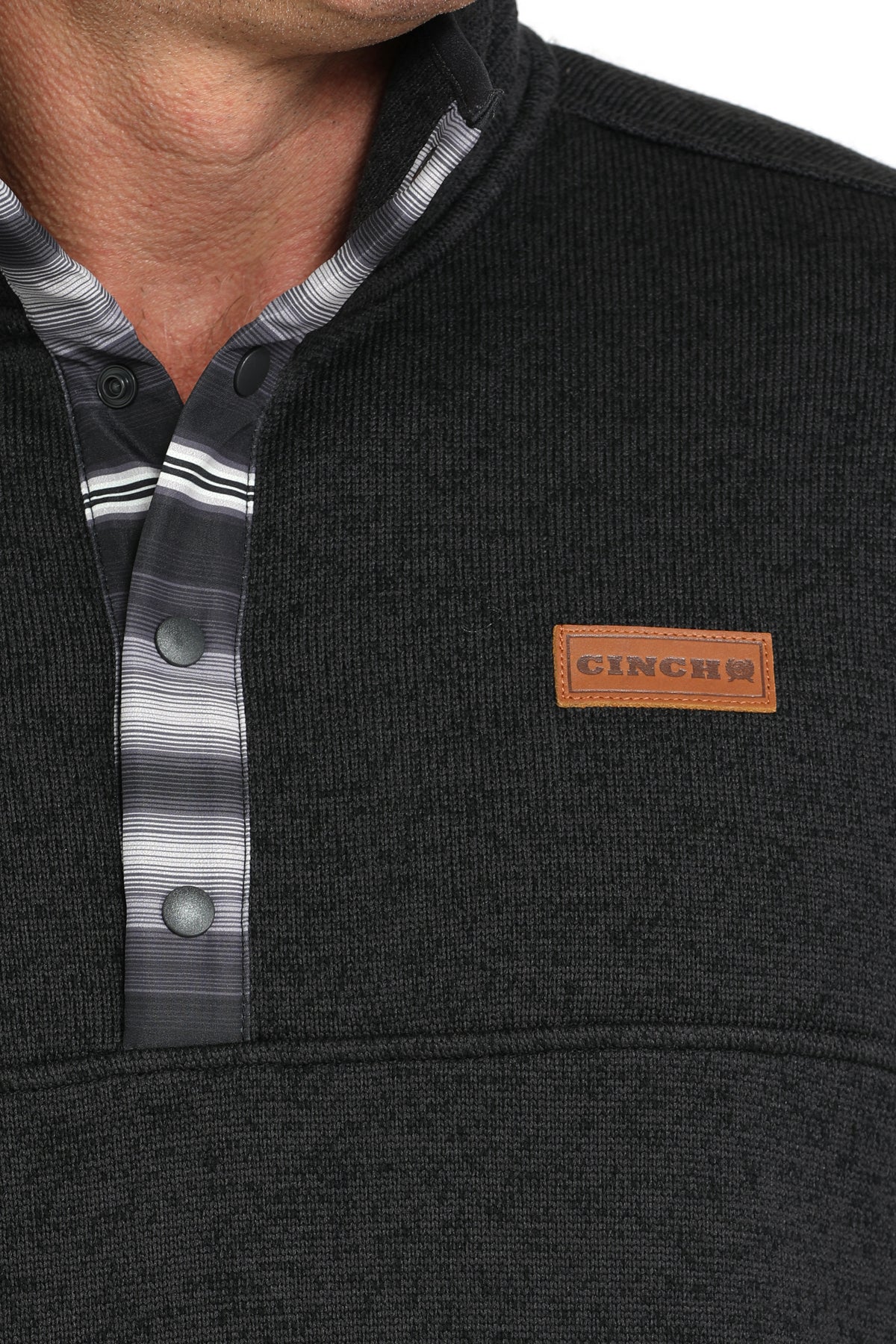 Close-up of a man wearing a dark gray pullover jacket with buttons and a 'CINCH' logo