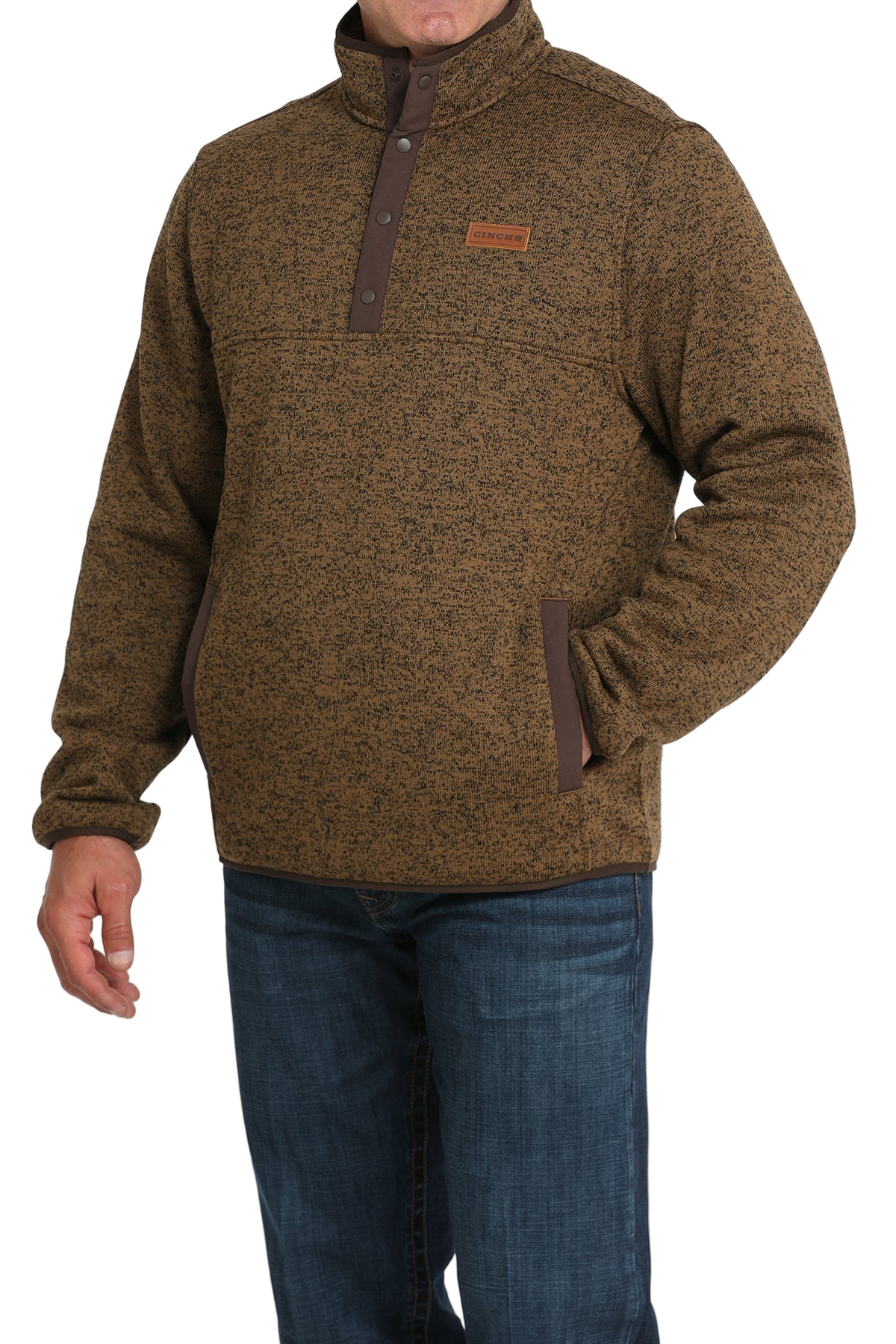 Man wearing a brown textured pullover with a snap-button placket, stand-up collar, and front hand pockets, paired with blue jeans