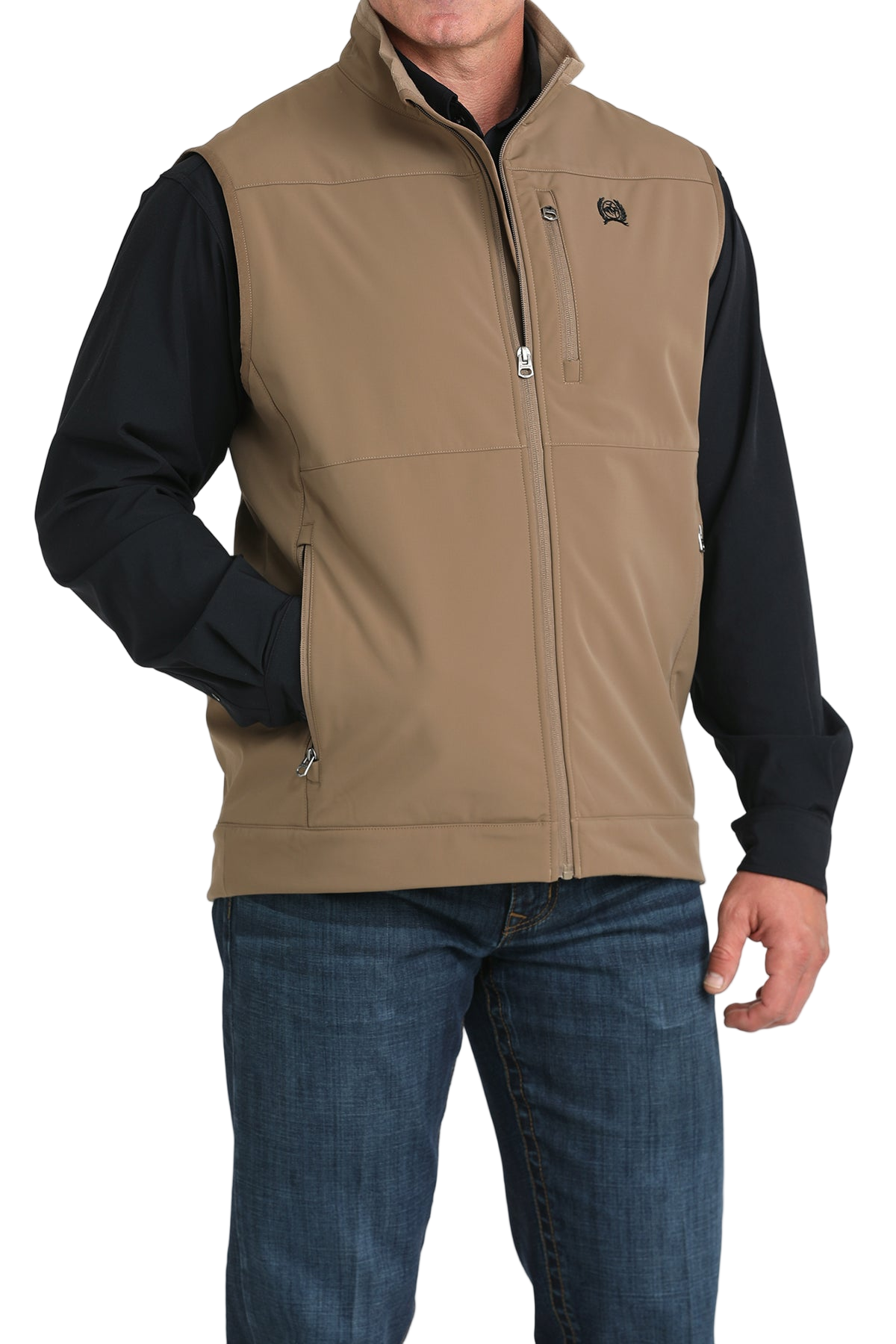 Man wearing a tan zip-up vest over a black long-sleeve shirt and jeans 