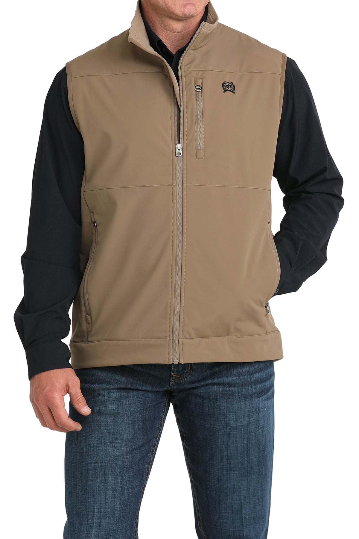 Man wearing a tan zip-up vest over a black long-sleeve shirt and jeans 