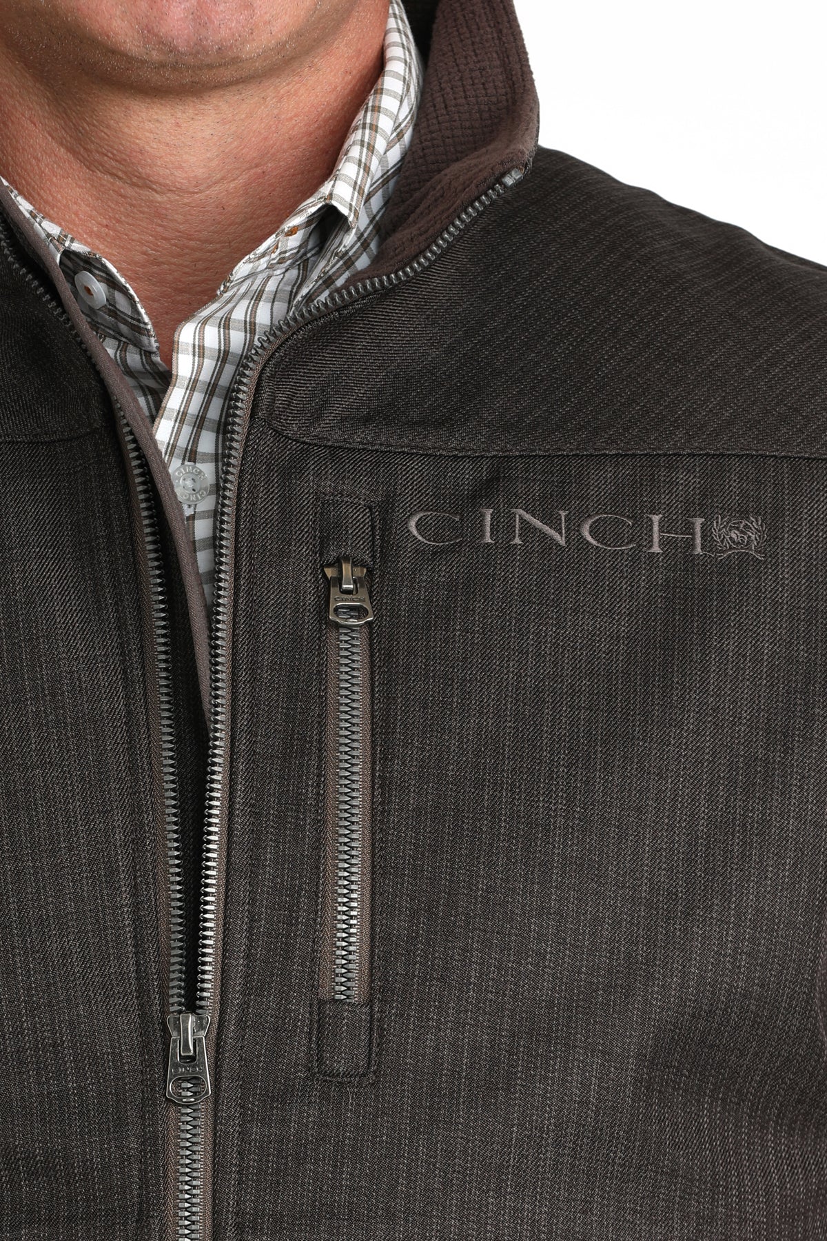 Close-up of a man wearing a brown vest with a cinch logo 