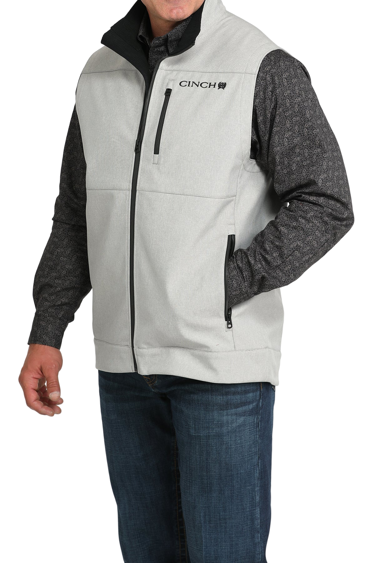 Man wearing a light gray zip-up vest over a gray long-sleeve shirt and jeans 