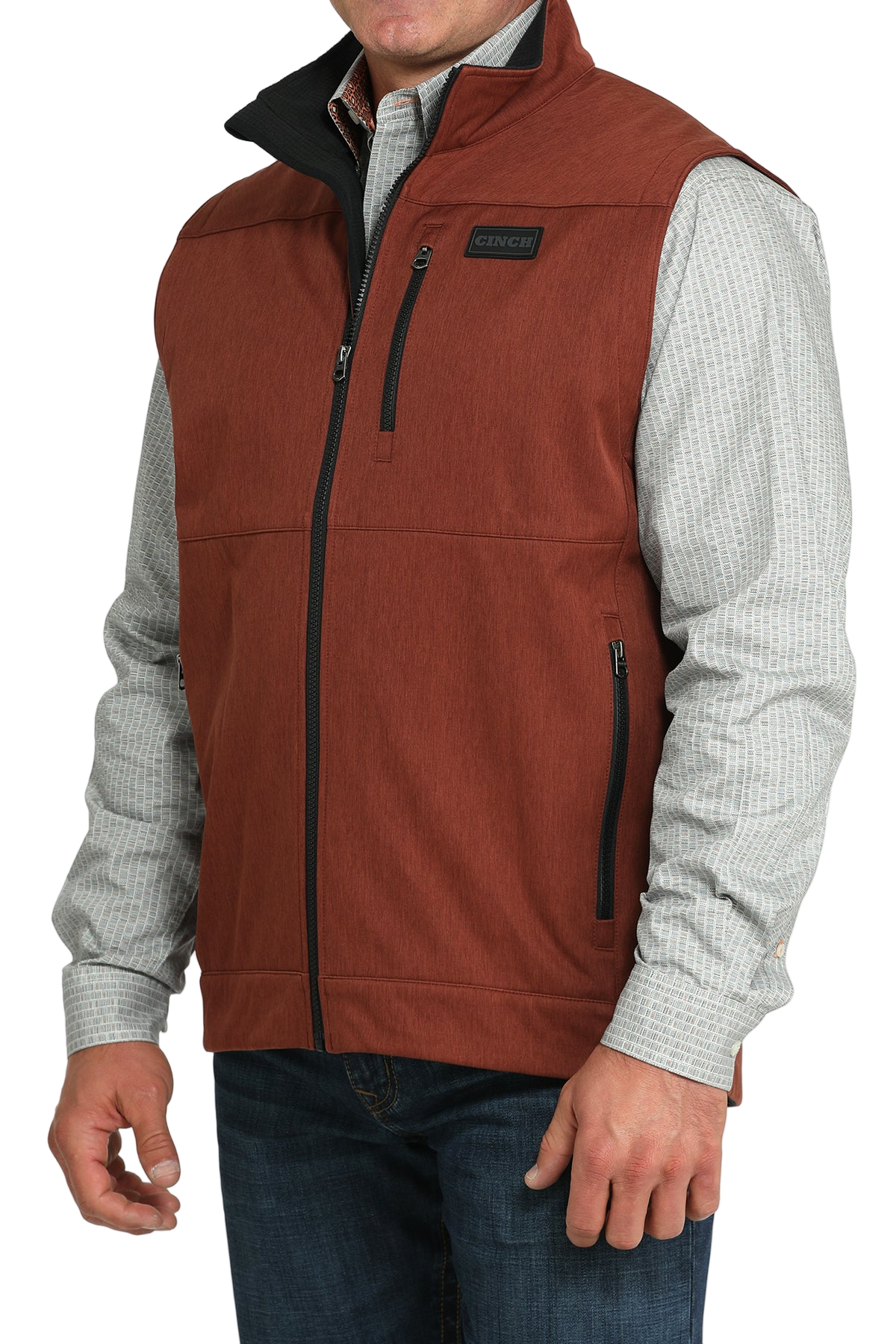 Man wearing a rust orange zip-up vest over a white long-sleeve shirt and jeans 