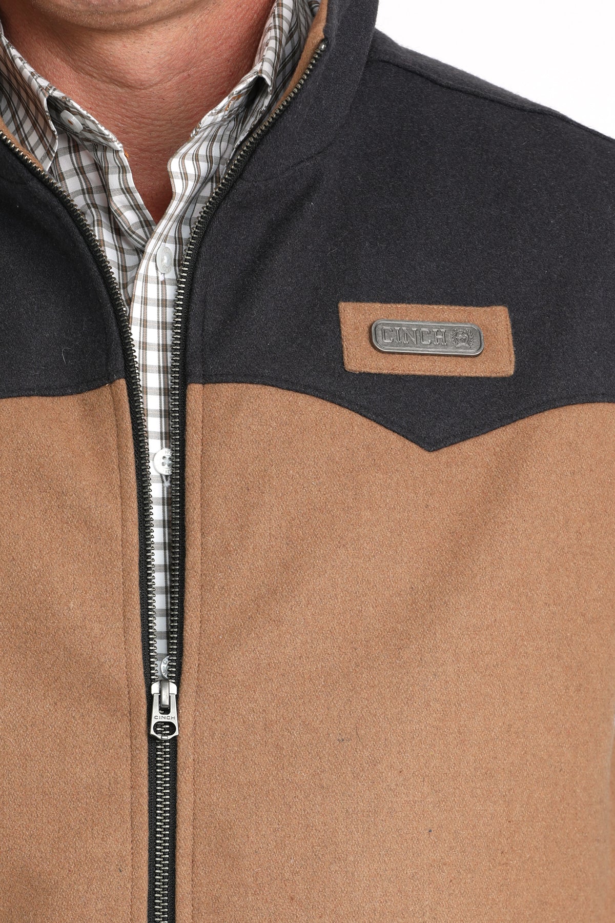 Close-up of a man wearing a brown vest with a cinch logo 