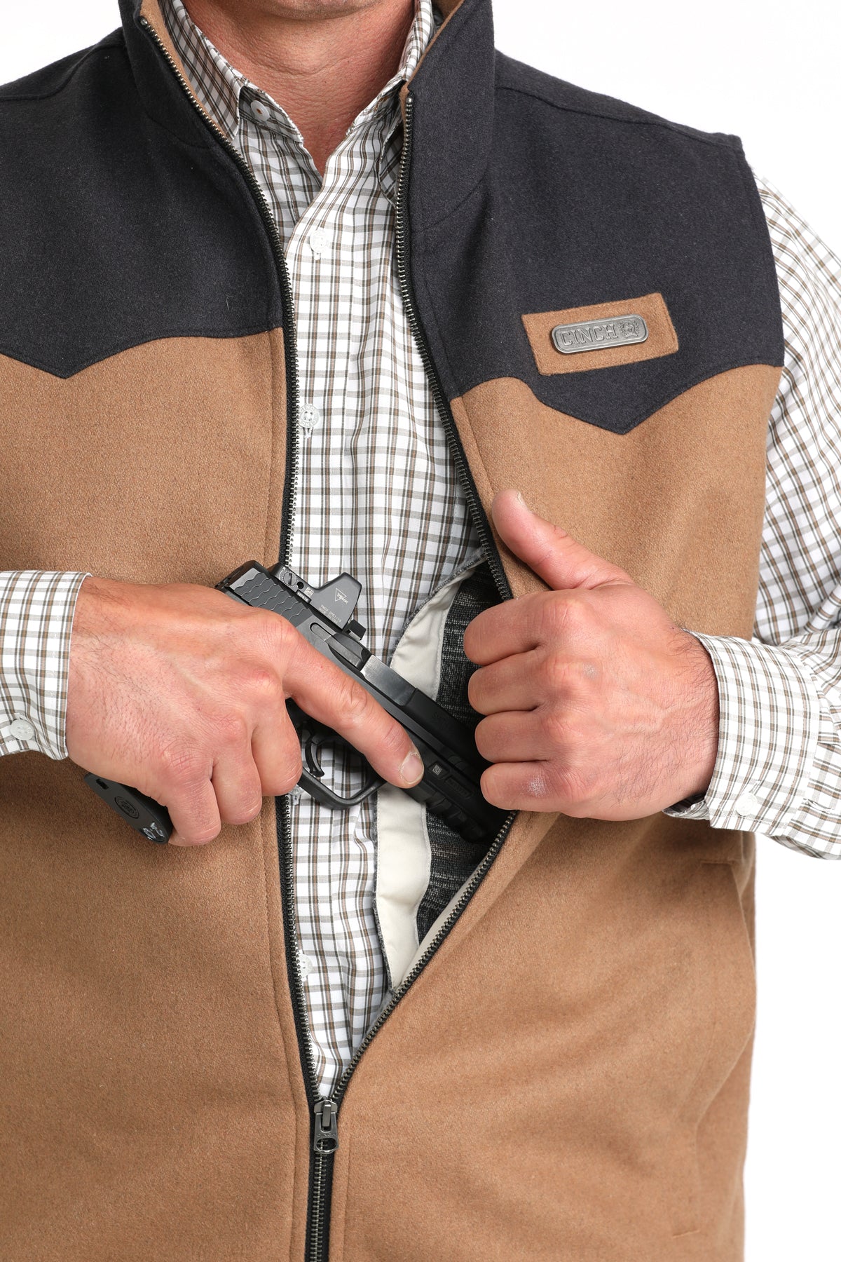 Man wearing a brown vest with a long sleeve button-down undershirt, partially showing a firearm going into the concealed carry pocket