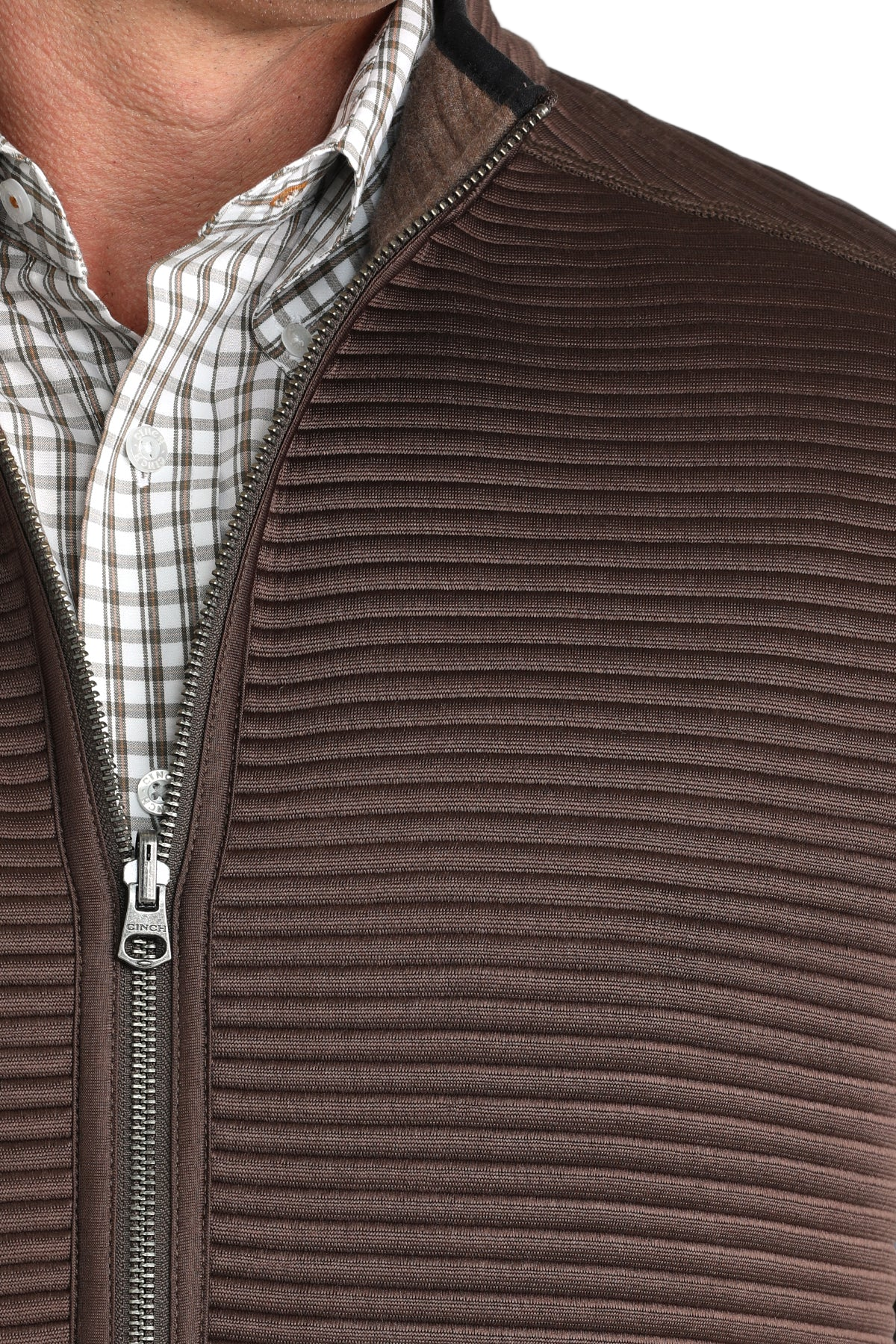 Close-up of a man wearing a brown zip-up vest over a white and brown checkered button-down shirt