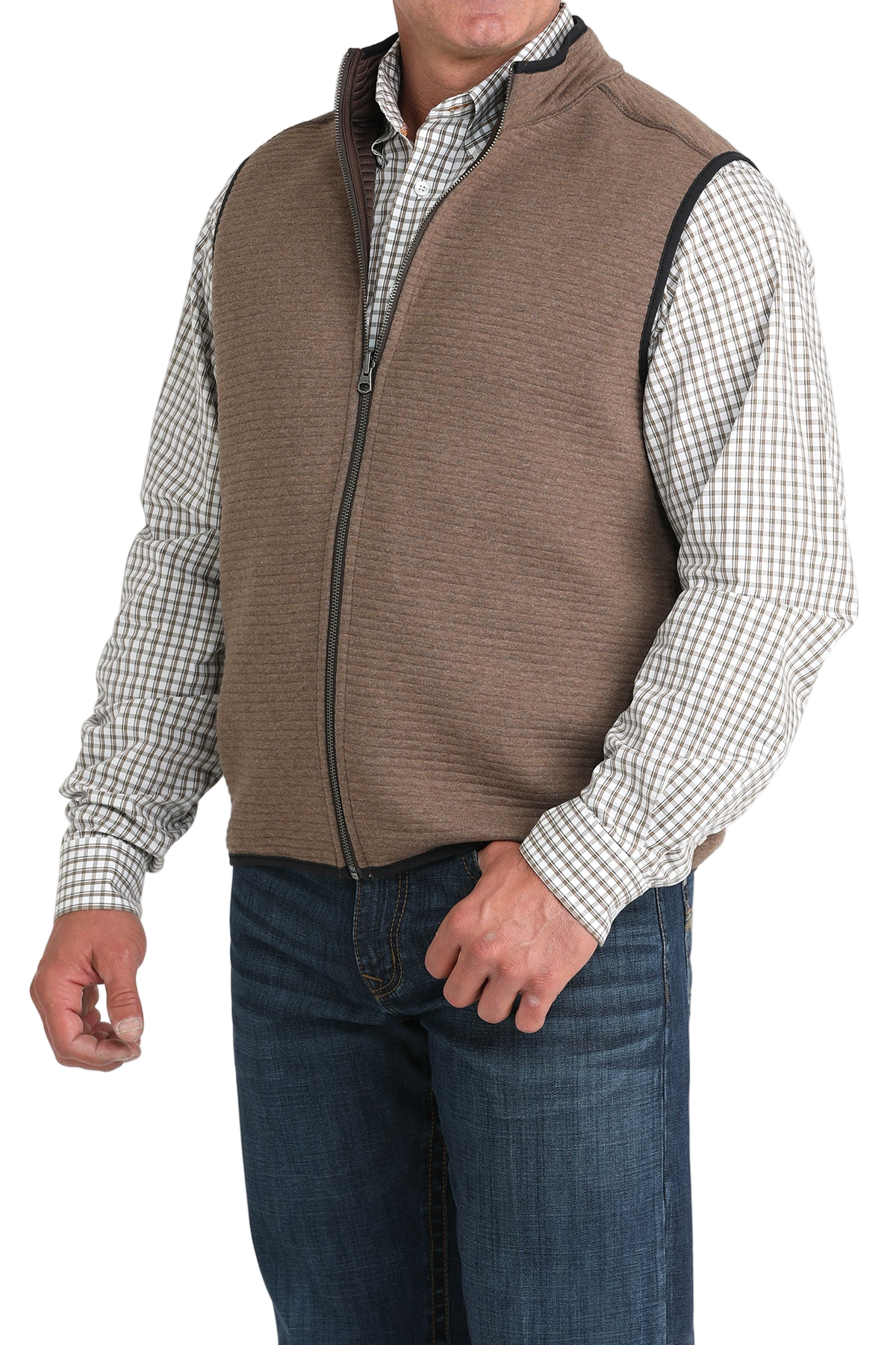 A man wearing a brown zip-up vest over a white and brown checkered button-down shirt, paired with blue jeans