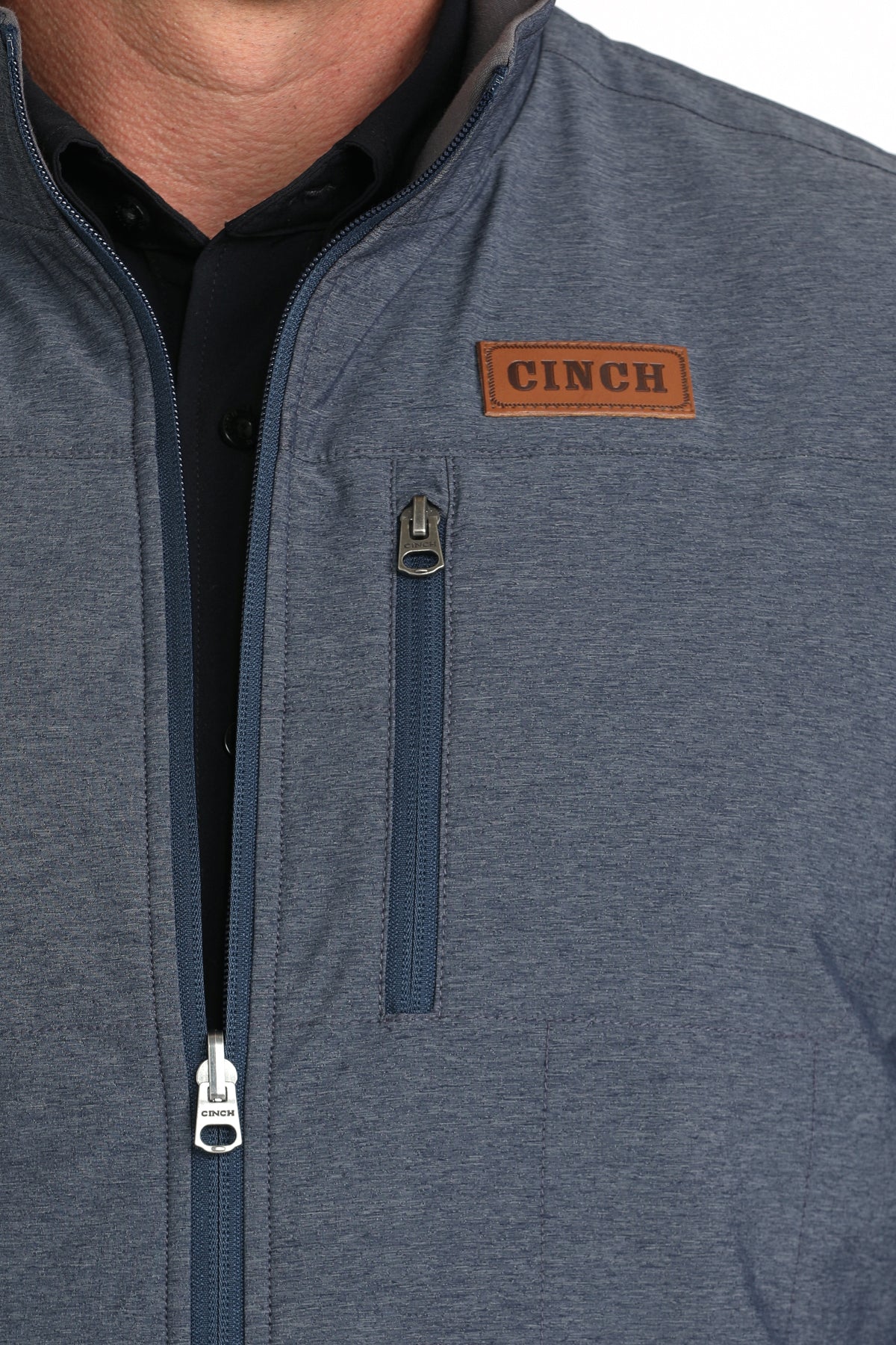 Close-up of a man wearing a blue vest with a black undershirt