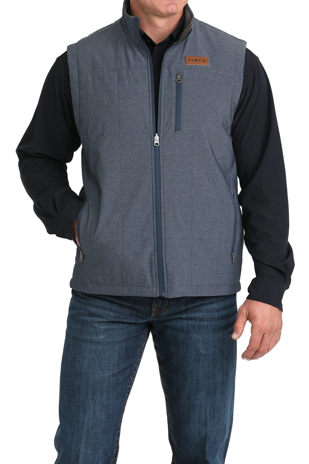 A man wearing a blue zip-up vest over a black shirt, paired with blue jeans