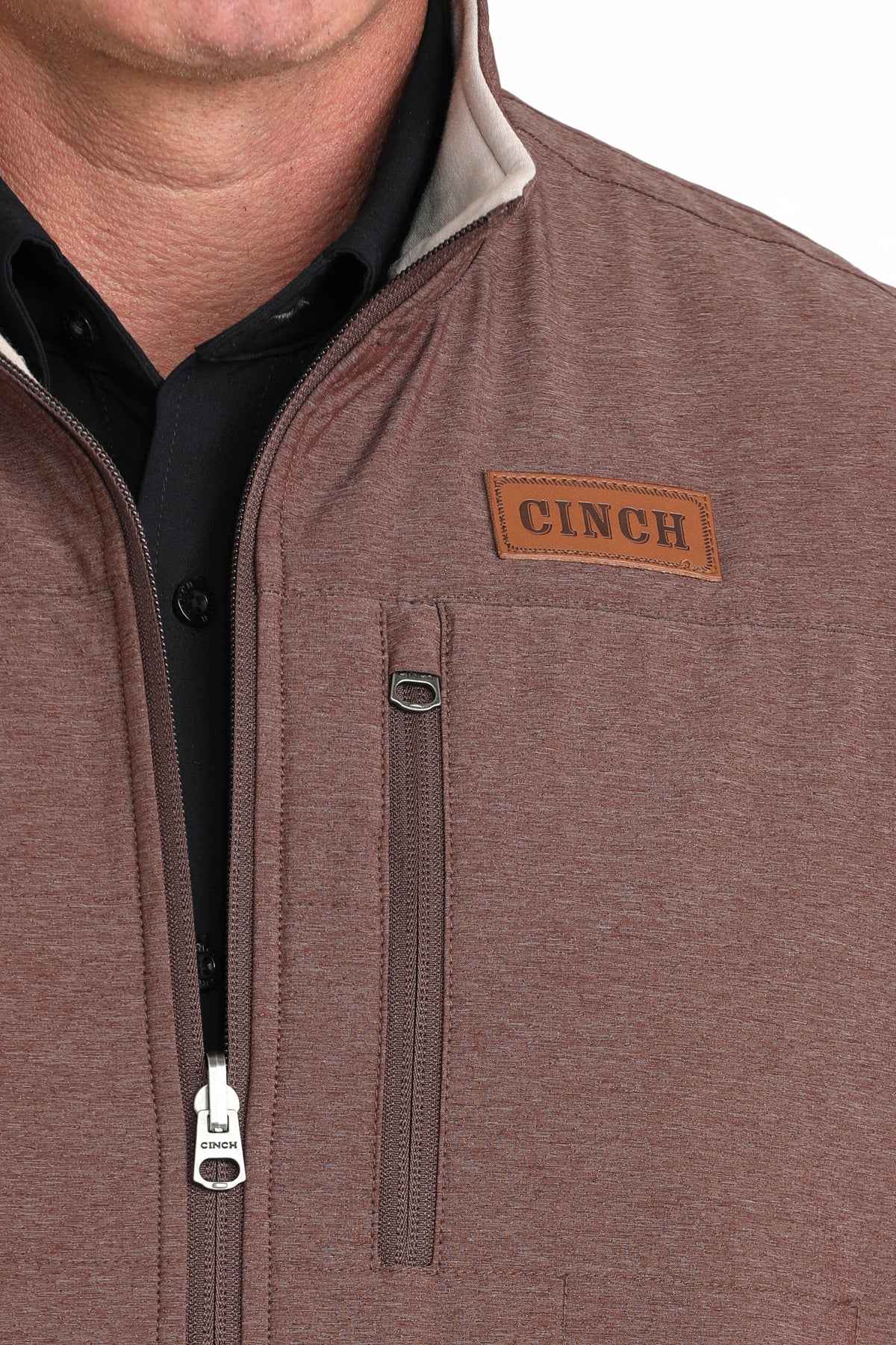 Close-up of a man wearing a burgundy vest with a black undershirt