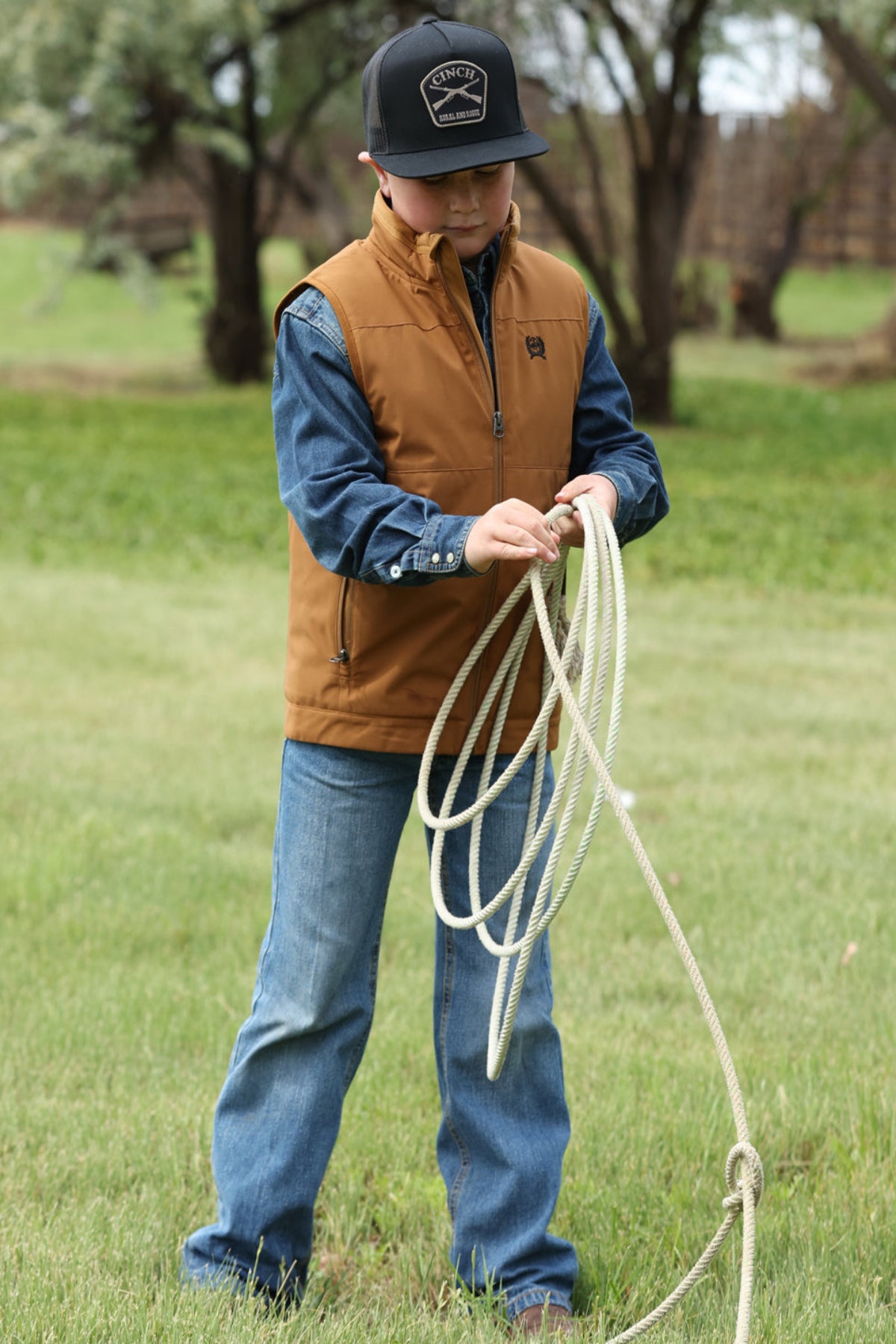 Person holding a lasso in a grassy outdoor setting