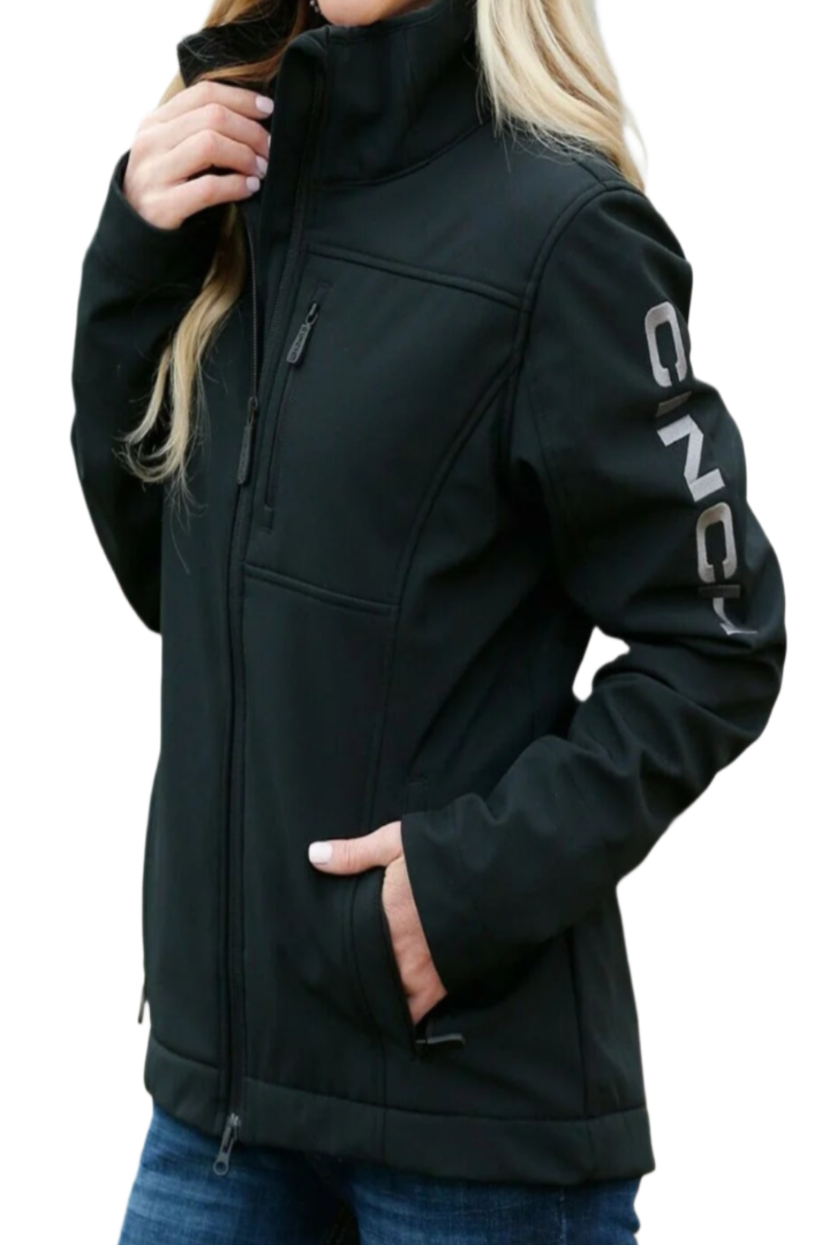 Woman wearing a black Cinch softshell jacket with CINCH branding down the sleeve and jeans on a white background