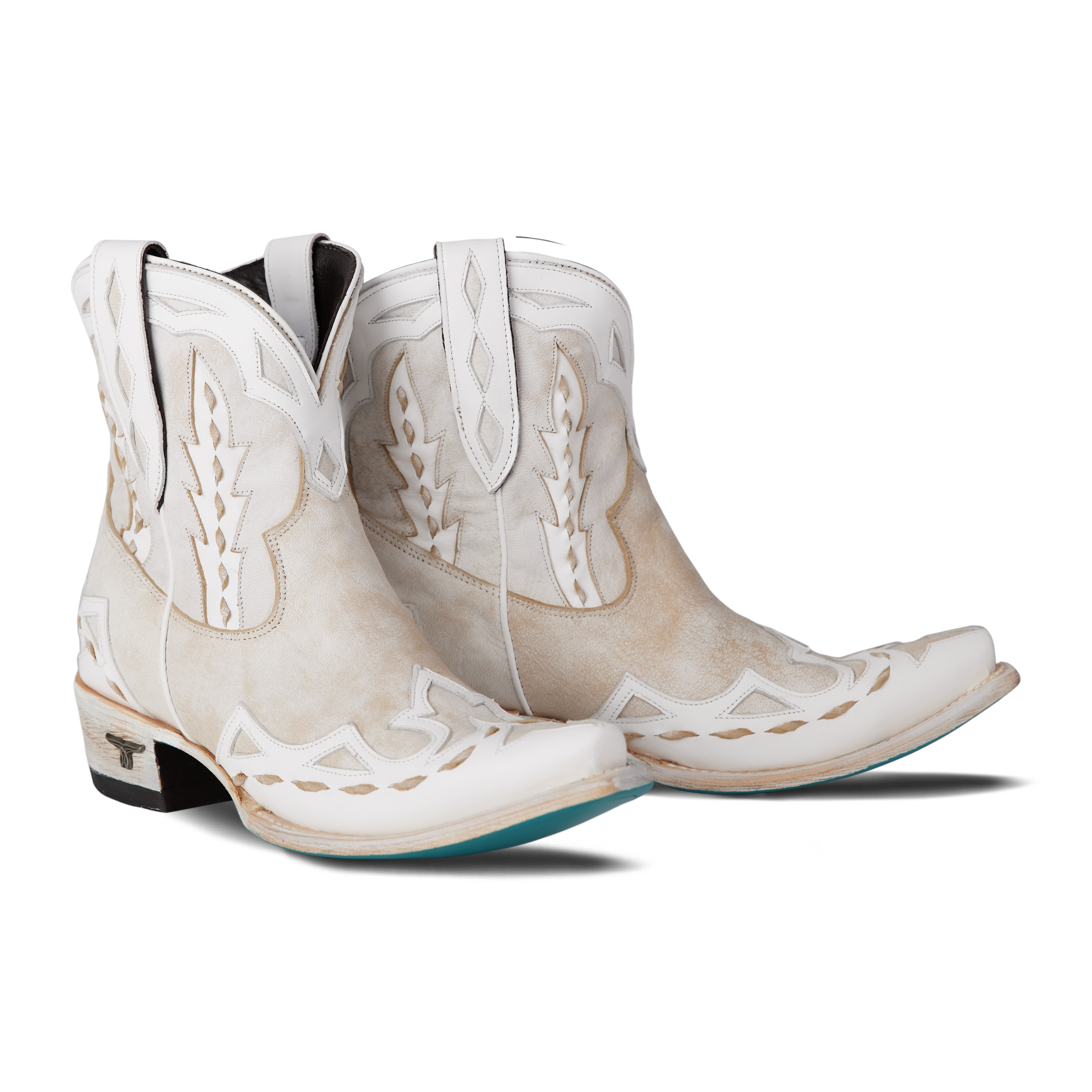 Pair of white cowboy boots with intricate designs on a white background