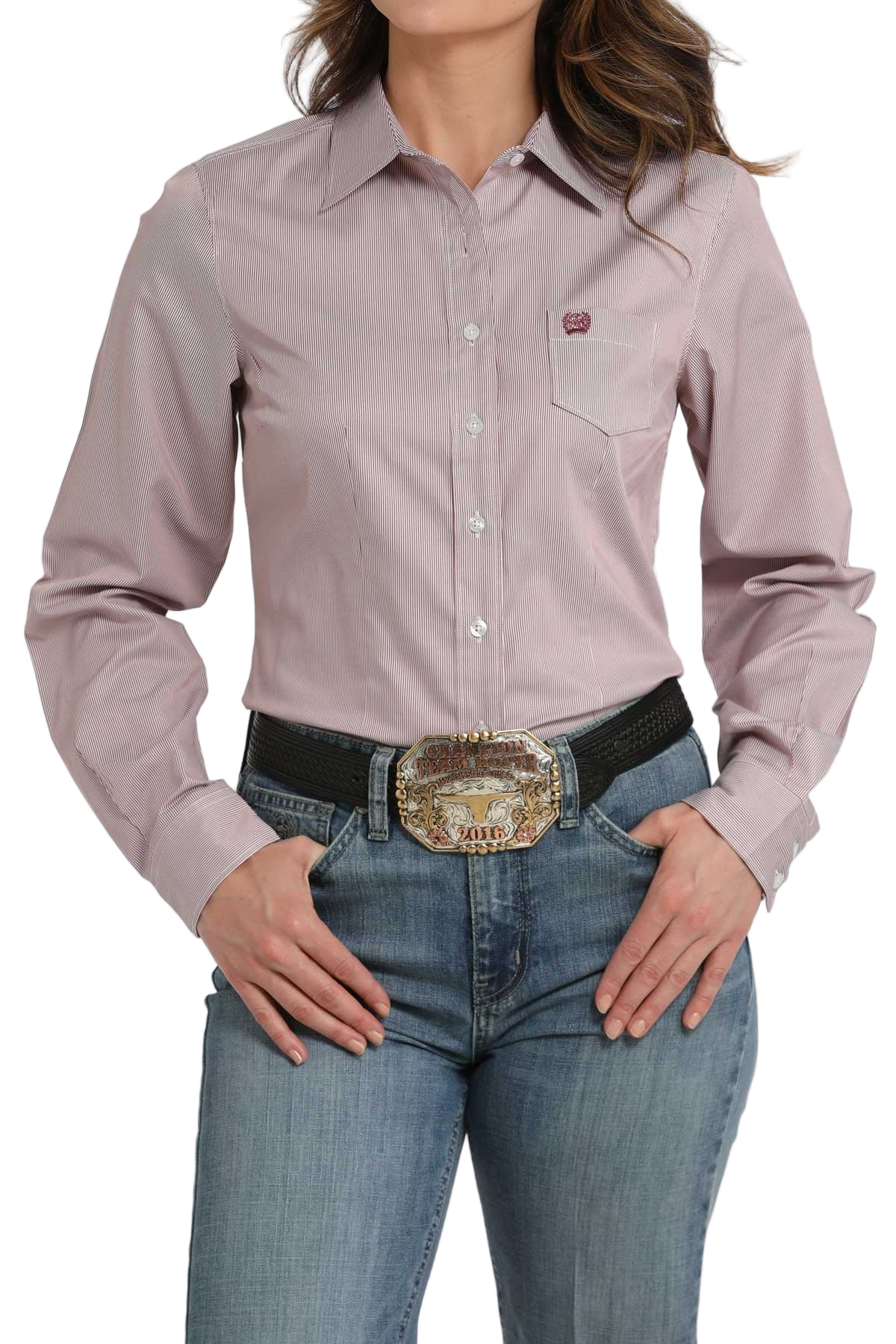 Woman wearing a pink striped long-sleeve button-down shirt, paired with jeans and a large western belt buckle