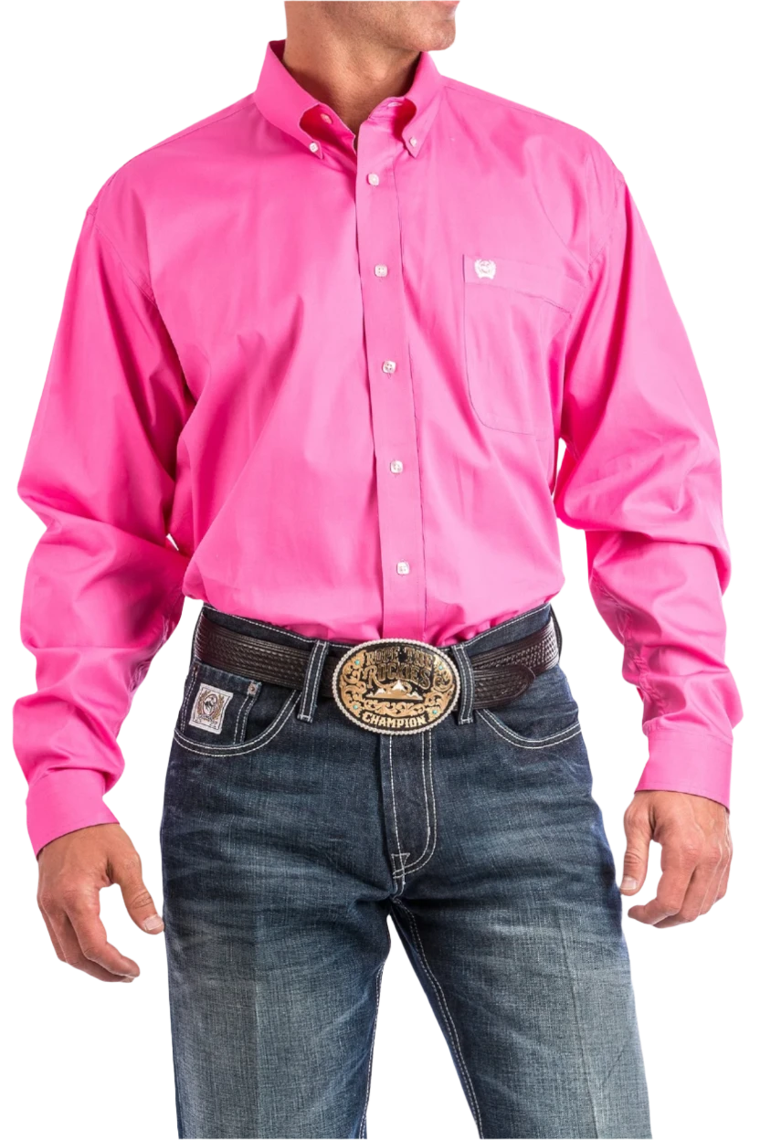 A man wearing a long-sleeve pink Western shirt with a button-down collar, paired with blue jeans and a belt with a decorative buckle.