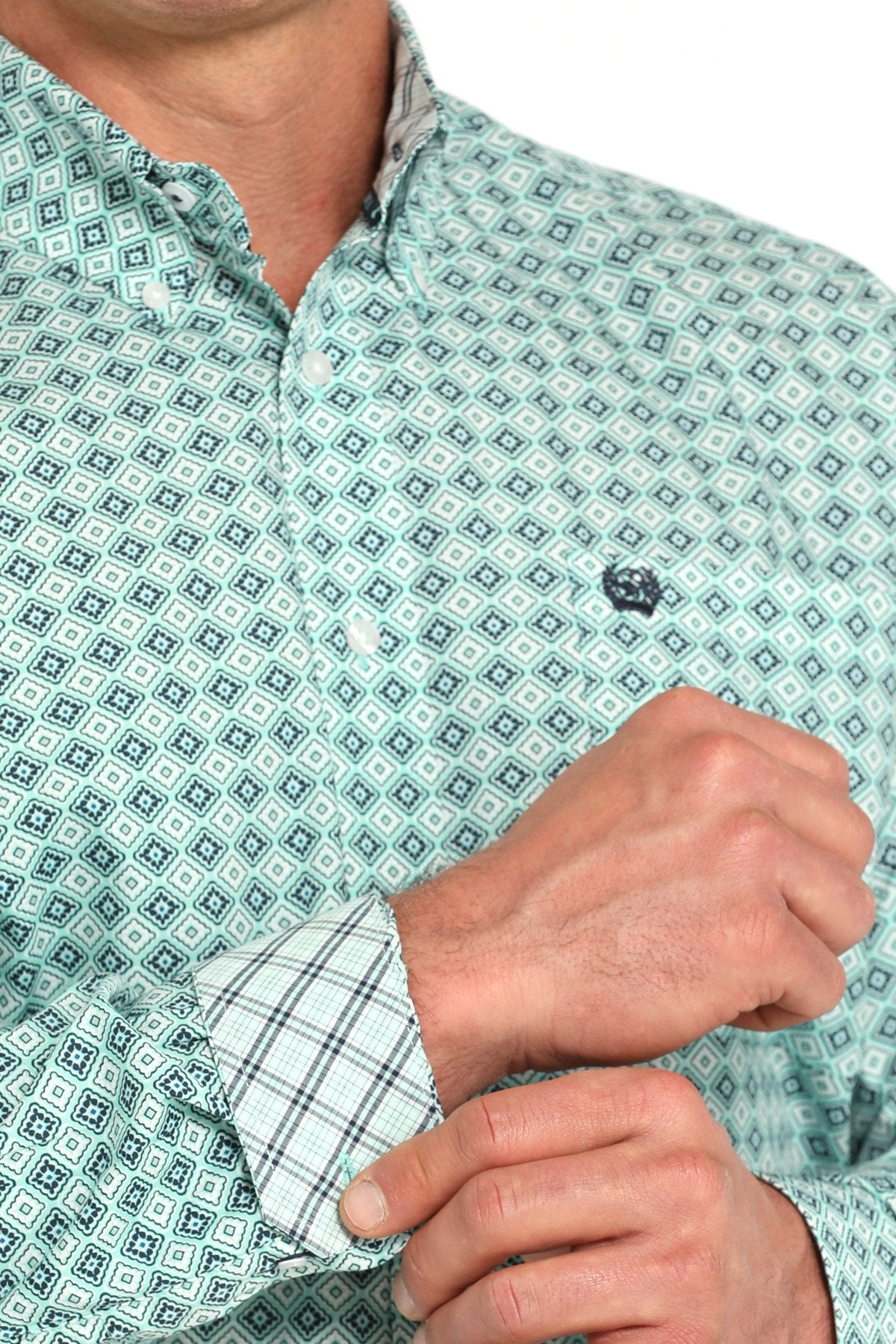 Close-up view of a turquoise long-sleeve button-down shirt with a medallion print pattern displayed on a white background.